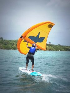 Elève avec voile en main glisse sur planche de wingfoil