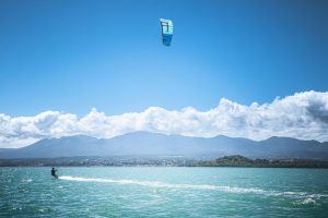 homme avec aile de kitesurf glisse sur lagon devant montagne soufrière en guadeloupe
